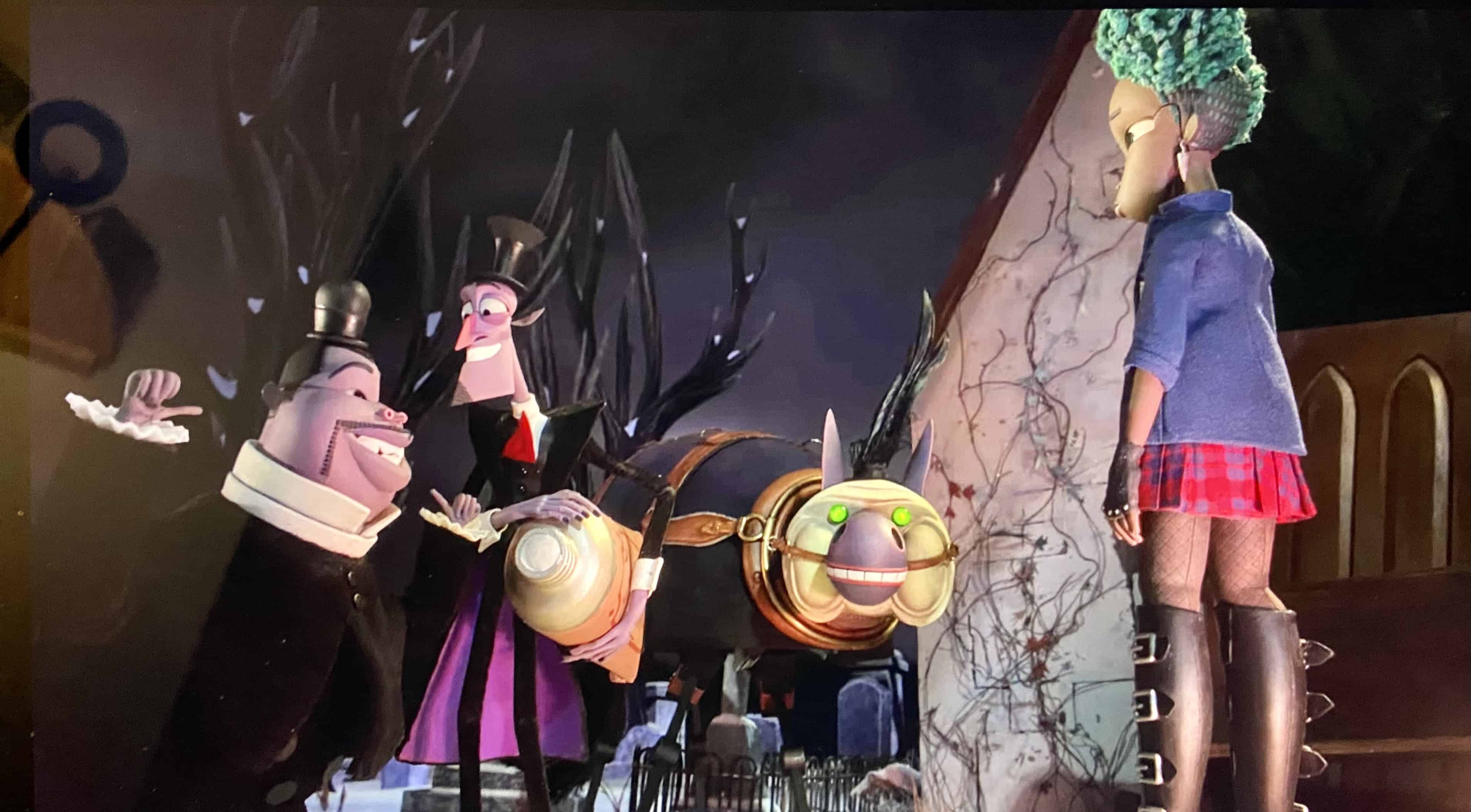 Kat troifft ihre Dämonen erstmals auf dem Friedhof. Das Maskottchen der Dämonen schaut neugierig hinter einem Grabstein hervor. (c) Wendell & Wild. Netflix.