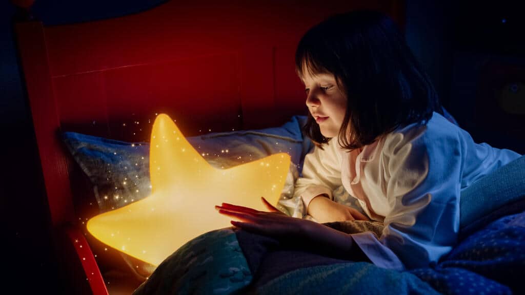 Screenshot aus LAURAS STERN. Laura sitzt mit dem ihr zugelaufenen Stern im Bett und spricht mit ihm