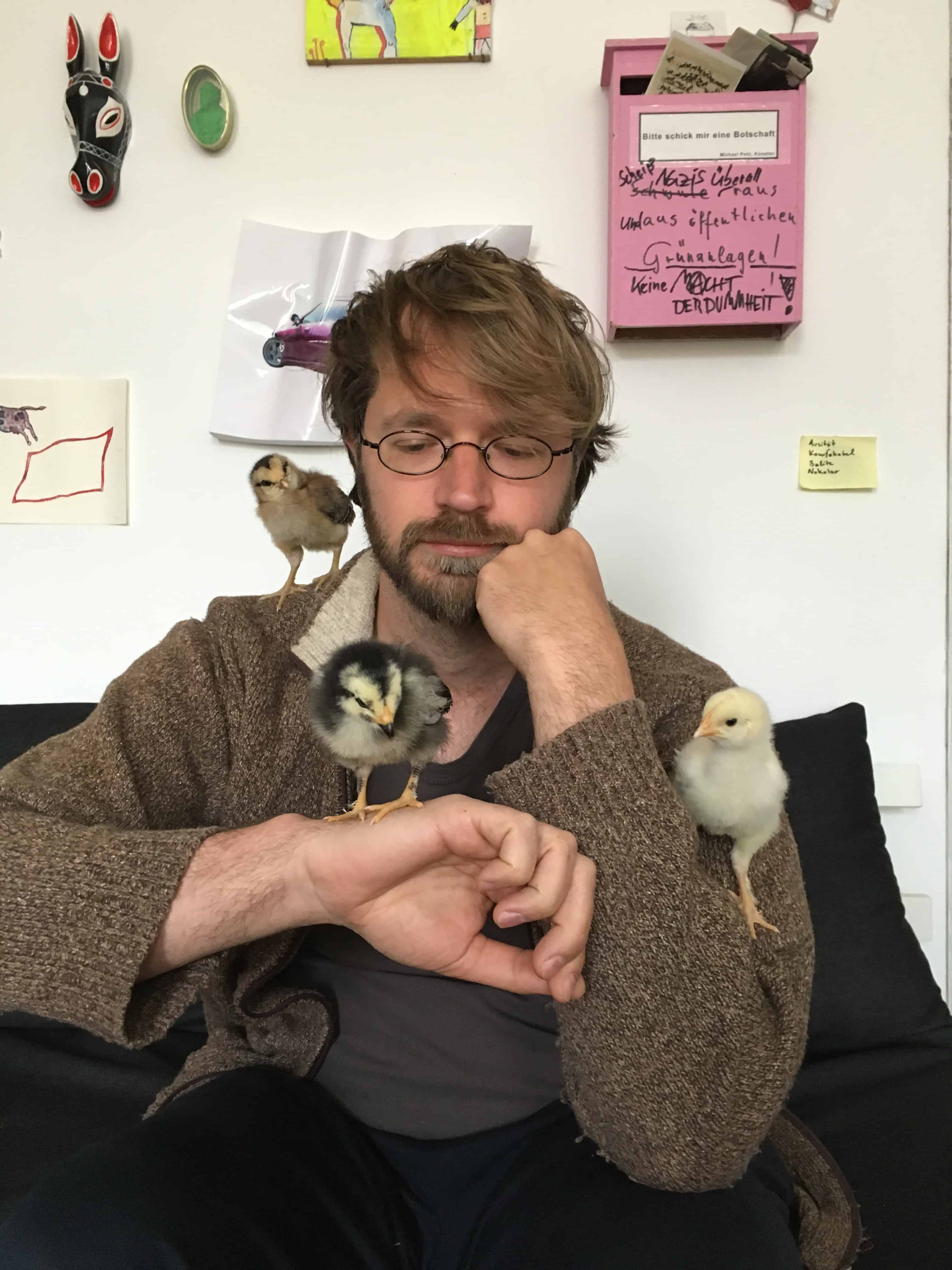 Sebastian Meschenmoser mit drei Küken auf Schultern und Armen.